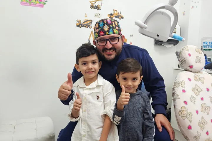 Odontopediatra con dos niños en un consultorio dental infantil